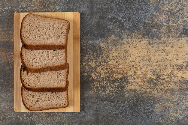 In Scheiben geschnittenes frisches Roggenbrot auf Holzbrett.