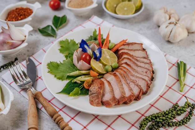 In Scheiben geschnittenes gebratenes Schweinefleisch mit Zitrone, Zwiebel, roter Zwiebel, Tomate, langer Bohne, Schmetterlingserbse Blume und Minze.