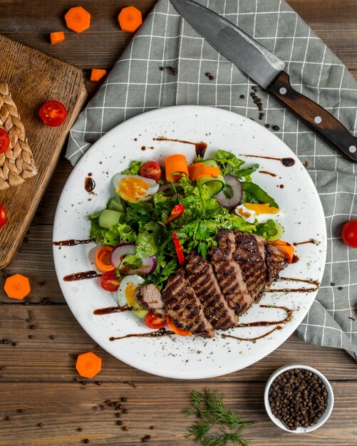 In Scheiben geschnittenes gegrilltes Rindersteak, serviert mit grünem Salat mit Eiern