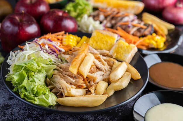 In Scheiben geschnittenes Hühnchensteak mit Brot, Karotten, Blumenkohl, Rüben und Mais auf einem schwarzen Teller.