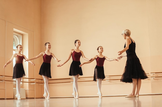 In voller Länge vom Ballettlehrer, der einer Gruppe von Ballerinas eine Tanzklasse hält