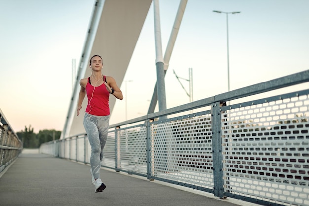 In voller Länge von der athletischen Frau, die über die Brücke läuft