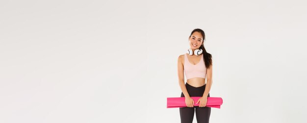 In voller Länge von niedlichen asiatischen Mädchen wie Fitness-Holding-Gummimatte für Übungen oder Yoga-Kurse