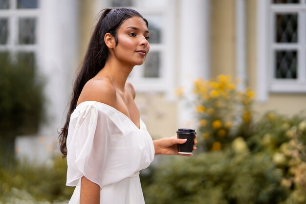 Indische Frau der Seitenansicht, die Kaffeetasse hält