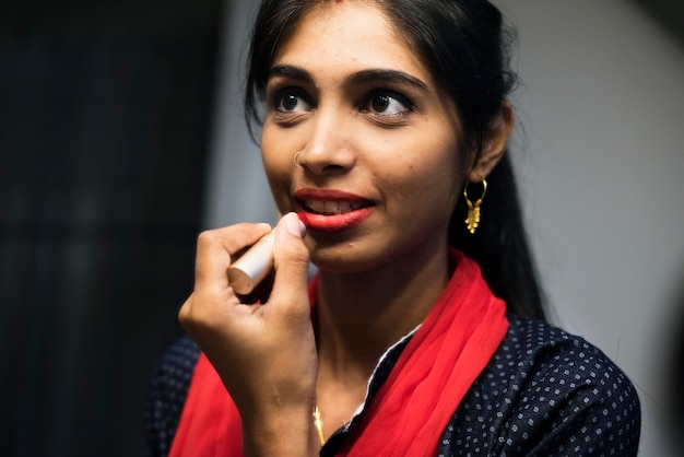 Indische Frau, die auf einen Lippenstift sich setzt