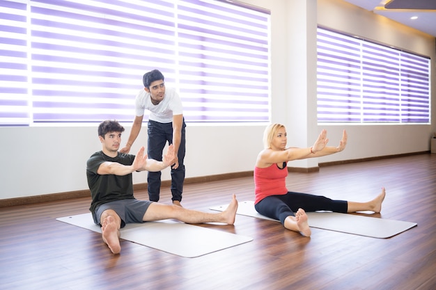 Indischer Lehrer hilft Studenten an der Yogaklasse