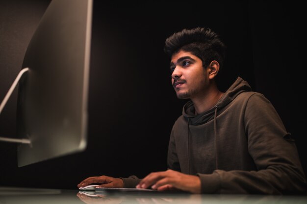 Indischer Mannhacker, der Computer verwendet, um Daten auf Schreibtisch zu stehlen