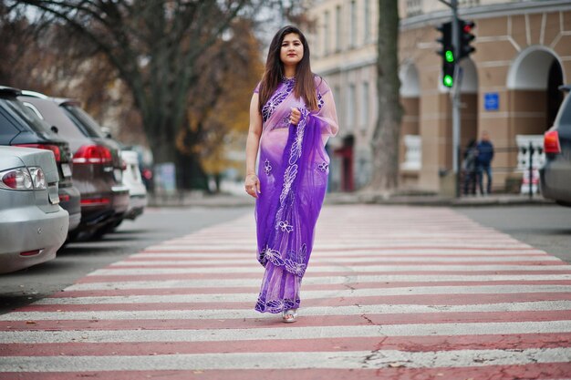 Indisches hinduistisches Mädchen im traditionellen violetten Saree posierte auf der Straße, die am Fußgängerüberweg spazieren ging