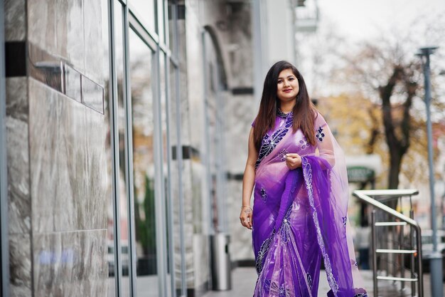 Indisches hinduistisches Mädchen im traditionellen violetten Saree posierte auf der Straße