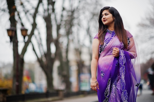 Indisches hinduistisches Mädchen im traditionellen violetten Saree posierte auf der Straße