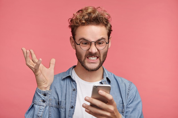 Indoor-Porträt eines bärtigen jungen Mannes mit trendiger Frisur