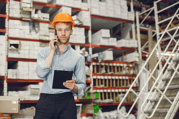 Industriearbeiter drinnen in der Fabrik. Geschäftsmann mit orangefarbenem Schutzhelm. Mann in einem blauen Hemd.