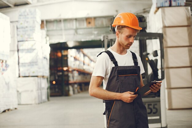 Industriearbeiter drinnen in der Fabrik. Junger Techniker mit orangefarbenem Schutzhelm.