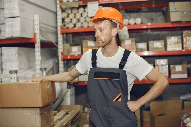 Industriearbeiter drinnen in der Fabrik. Junger Techniker mit orangefarbenem Schutzhelm.