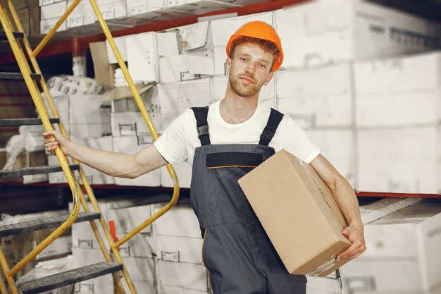 Industriearbeiter drinnen in der Fabrik. Junger Techniker mit orangefarbenem Schutzhelm.