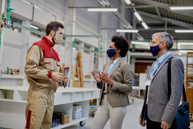 Industriearbeiter im Gespräch mit Unternehmensleitern in der Produktionsstätte während der COVID19-Pandemie