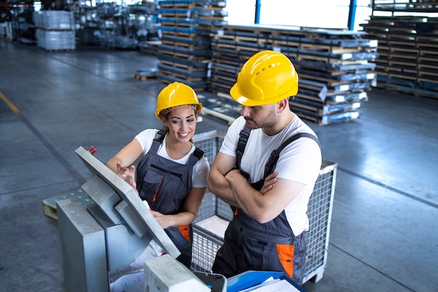 Kostenloses Foto industriemitarbeiter mit gelbem helm bedienen maschinen an der produktionslinie unter verwendung eines neuen software-computers