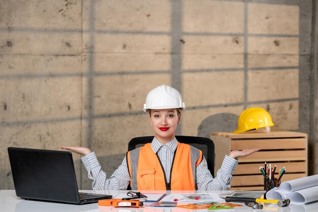 Ingenieur-Bauarbeiter in Helm und Weste, intelligentes, junges, süßes blondes Mädchen, das sich über den Plan freut