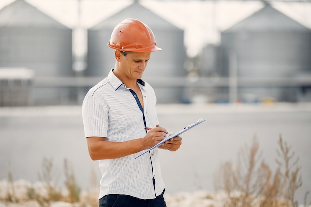 Ingenieur in einem Helm, der zur Fabrik steht