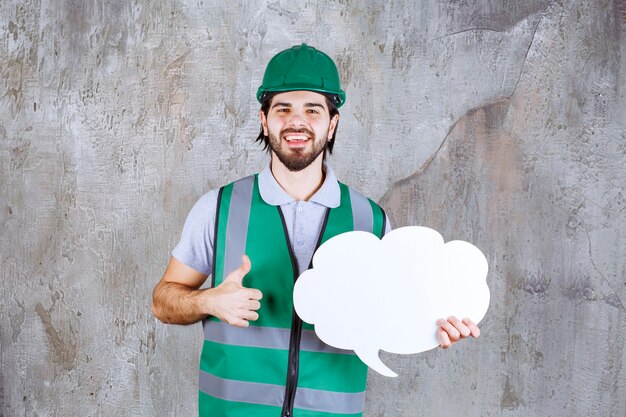 Ingenieur in gelber Ausrüstung und Helm, der eine Infotafel in Wolkenform hält und dieses Projekt genießt