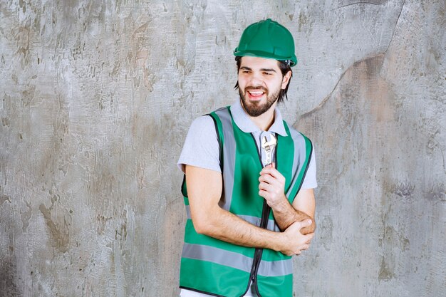 Ingenieur in gelber Ausrüstung und Helm mit einem metallischen Schraubenschlüssel.