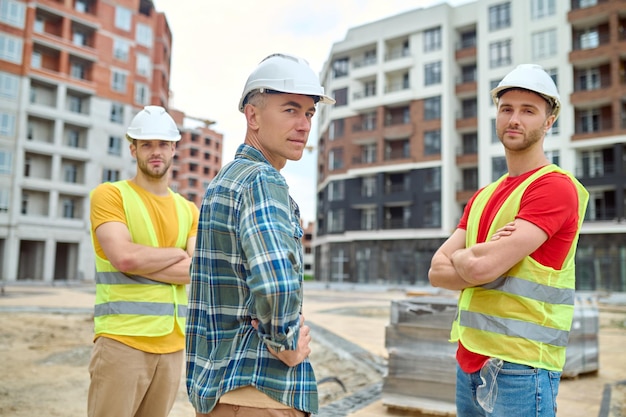 Ingenieur und zwei Arbeiter, die in die Kamera schauen