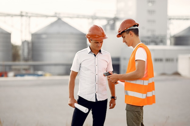 Ingenieure in einem Helm, der zur Fabrik steht