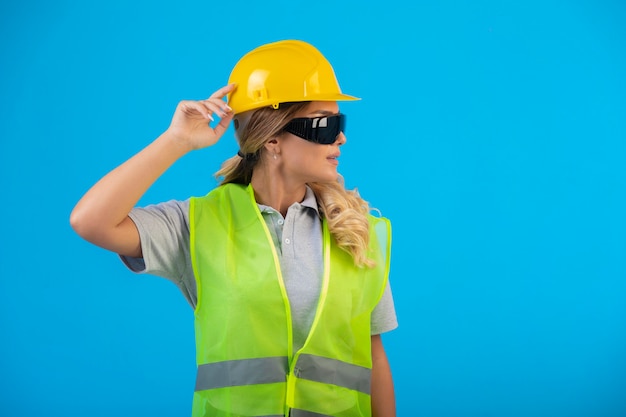 Ingenieurin in gelbem Helm und Ausrüstung, die eine strahlverhindernde Brille trägt und sich sicher fühlt.