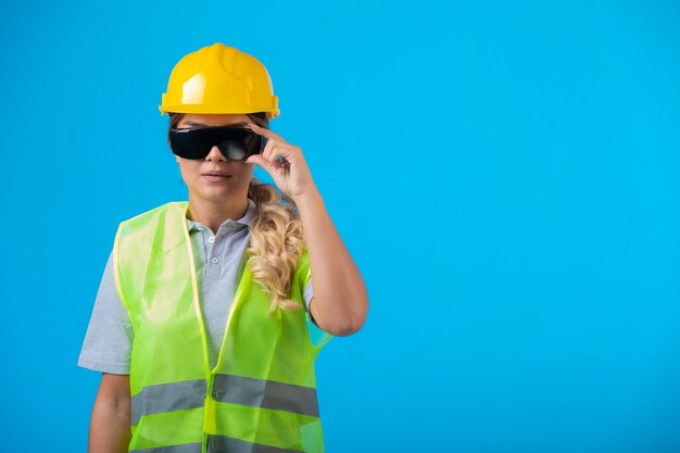 Ingenieurin in gelbem Helm und Ausrüstung mit strahlpräventiver Brille, die sich als Profi ausgibt.