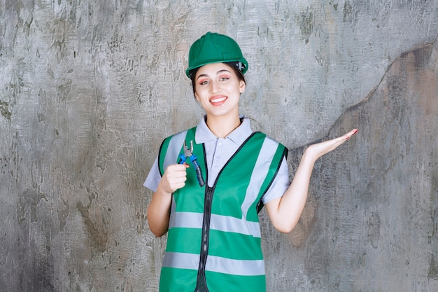 Kostenloses Foto ingenieurin in grünem helm mit zange für reparaturarbeiten