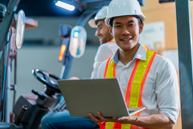 Ingenieurpersonal männlicher Lagerarbeiter mit Schutzhelm, der durch Logistikzentrum Lager Fabrik Baustelle Logistik Architekt Forklife Fahrer Mann Baumeister drinnen Hintergrund arbeitet