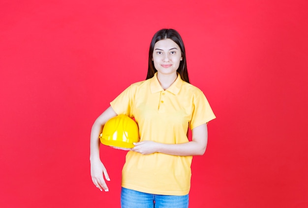 Ingenieursmädchen im gelben Dresscode mit einem gelben Schutzhelm