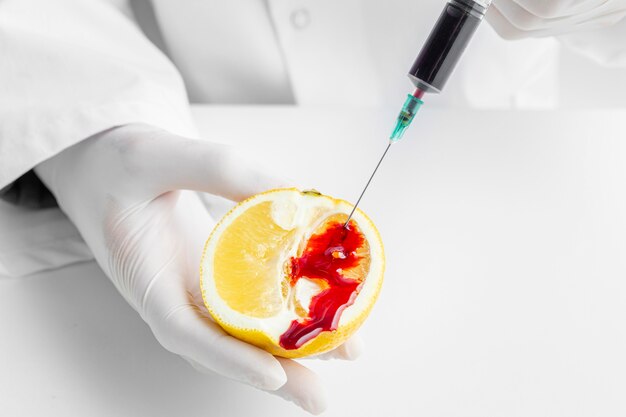 Injizieren von Chemikalien in eine Zitrusfrucht mit einer Spritze