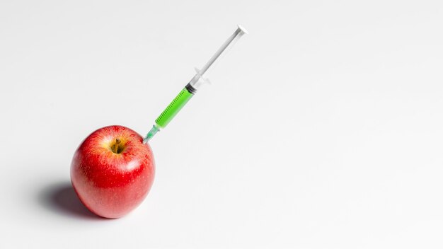 Injizieren von rotem Apfel mit grünen Chemikalien