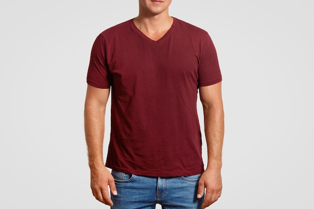 Innen beschnittenes Bild des muskulösen jungen Mannes im roten T-Shirt und in den Jeans