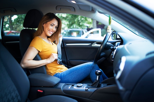 Innenansicht des Autos des weiblichen Fahrers, der Sicherheitsgurt anlegt