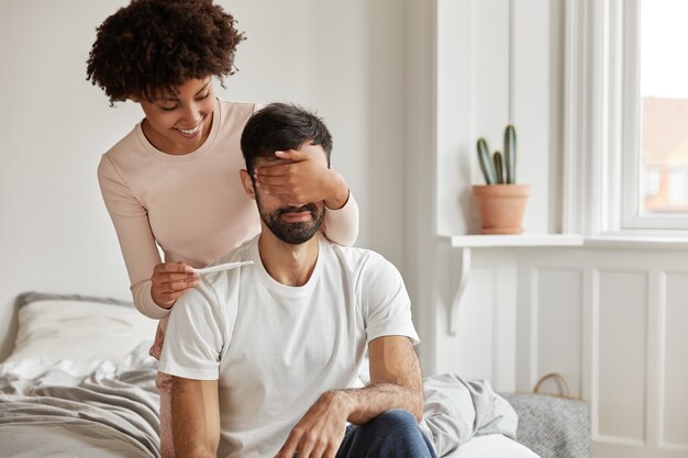 Innenaufnahme des glücklichen jungen Paares mit Schwangerschaftstest, der zu Hause aufwirft