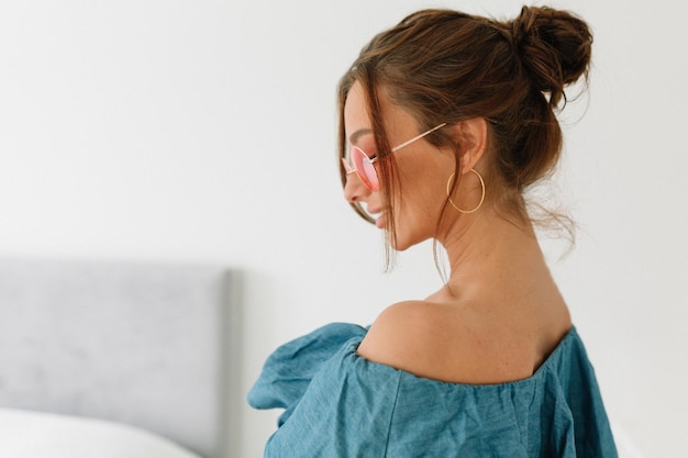 Innenaufnahme einer europäischen hübschen Frau mit dunklen Haaren, die ein blaues T-Shirt trägt und nach unten schaut und vor isoliertem Hintergrund steht