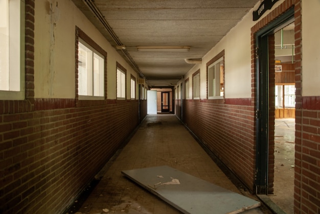 Innenaufnahme einer leeren Halle einer verlassenen Schule mit zerbrochenen Türen