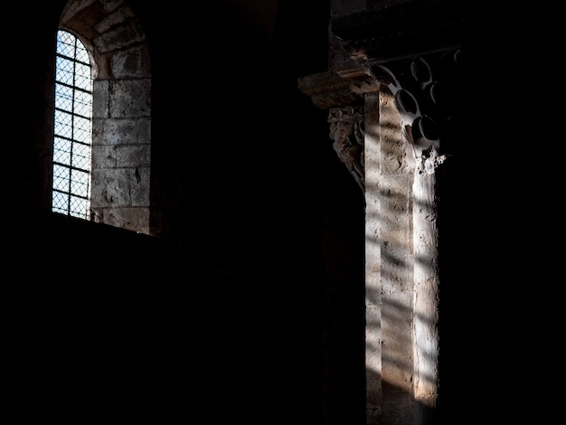 Innenaufnahme eines alten Gebäudes mit der Sonne, die durch das Fenster über der Säule scheint