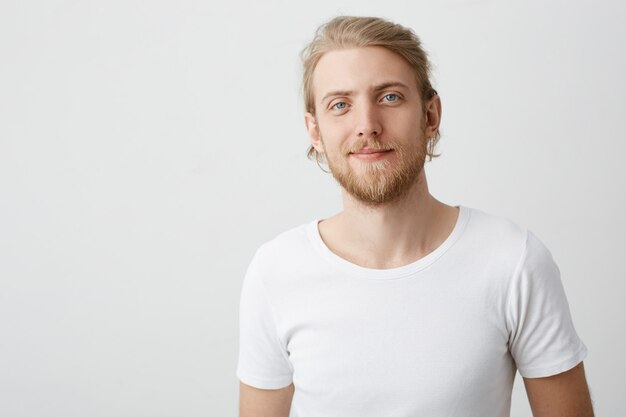 Innenaufnahme eines positiven gut aussehenden kaukasischen blonden Mannes mit grinsendem Bart und Schnurrbart