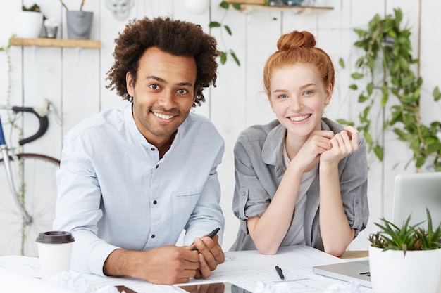 Innenporträt eines glücklichen vereinten multiethnischen Teams von zwei kreativen Arbeitern