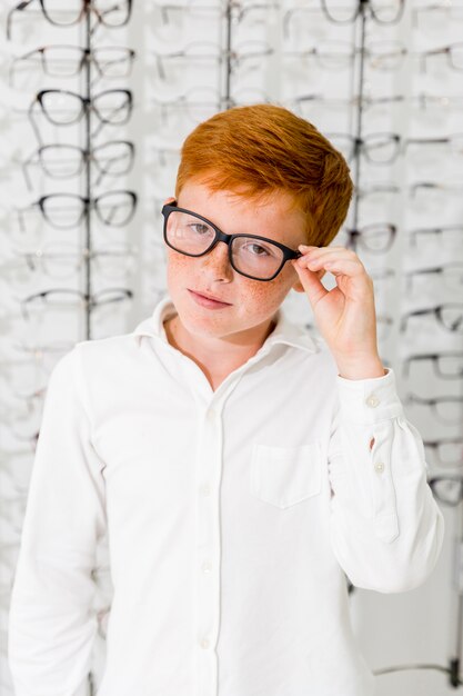 Innocent Junge mit schwarzem Rahmen Brillen Stehen bei Optik store