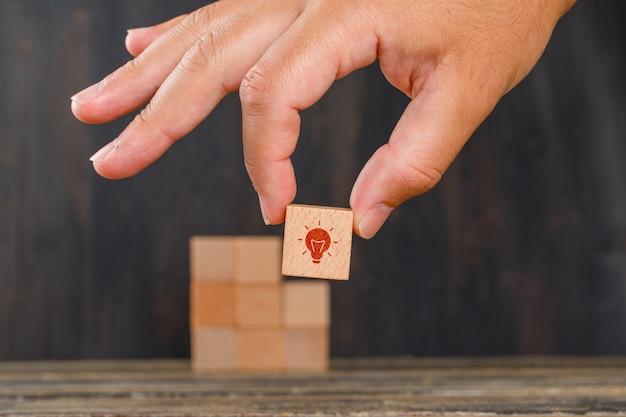 Innovationskonzept auf Holztischseitenansicht. Hand hält Holzwürfel mit Symbol.