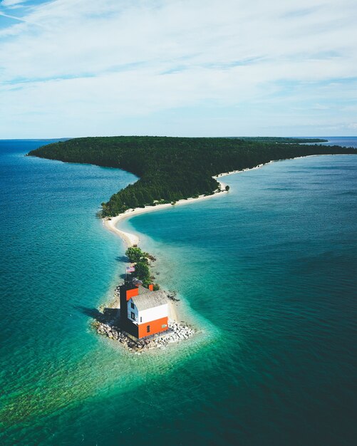 Insel bedeckt im Grünen, umgeben vom Meer mit einem kleinen Haus unter einem bewölkten Himmel