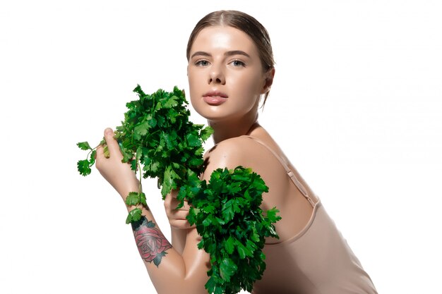 Inspiriert. Schließen Sie oben von der schönen jungen Frau mit den grünen Blättern auf ihrem Gesicht über Weiß. Kosmetik und Make-up, Natur- und Umweltbehandlung, Hautpflege