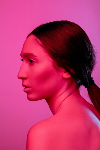 Inspiriert. Schönes Ostfrauenporträt lokalisiert auf rosa Studiohintergrund in Neon, Monochrom. Weibliches Brunettemodell. Konzept der menschlichen Emotionen, des Gesichtsausdrucks, des Verkaufs, der Anzeige, der Mode und der Schönheit.