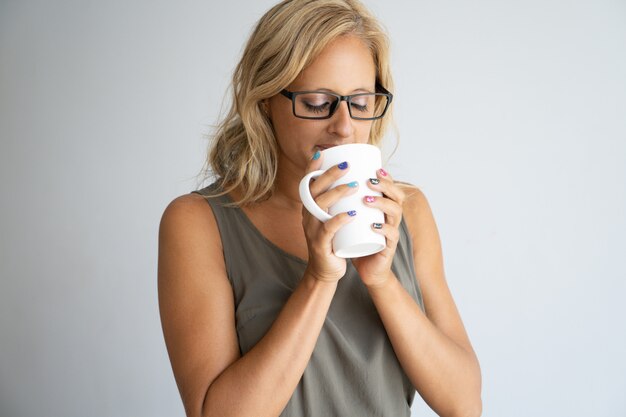 Inspirierter weiblicher Büroangestellter, der Kaffeepause genießt.