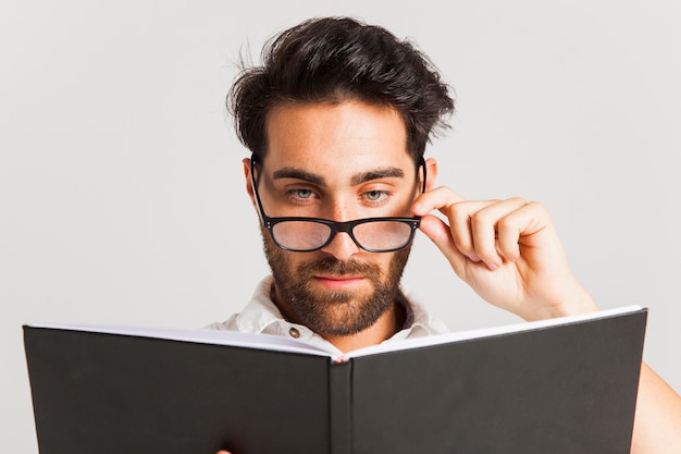 Intellektueller Mann posiert mit Brille und Buch