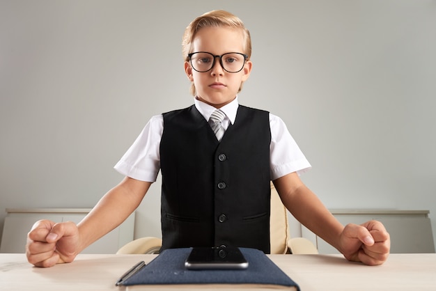 Intelligent gekleideter kaukasischer Junge, der im Büro steht und Fäuste auf Schreibtisch zuschlägt